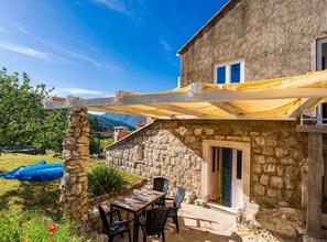 A stone building with a patio area, outdoor seating, and a view of the mountains. - Ranch House Zora (Dubrovnik)