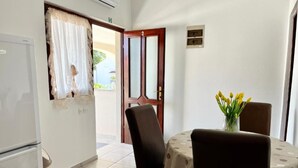 A small dining area with a table and chairs, a refrigerator, and a door leading outside. - Apartments Rio (Biograd na Moru)