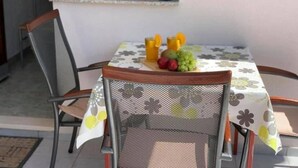A dining area with a table set for two, a chair, and a window with a view. - Apartments Rio (Biograd na Moru)