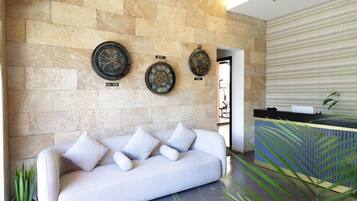 Un moderno vestíbulo con pared de piedra, un sofá blanco y una recepción.