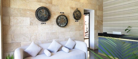 A modern lobby with a stone wall, a white sofa, and a reception desk.