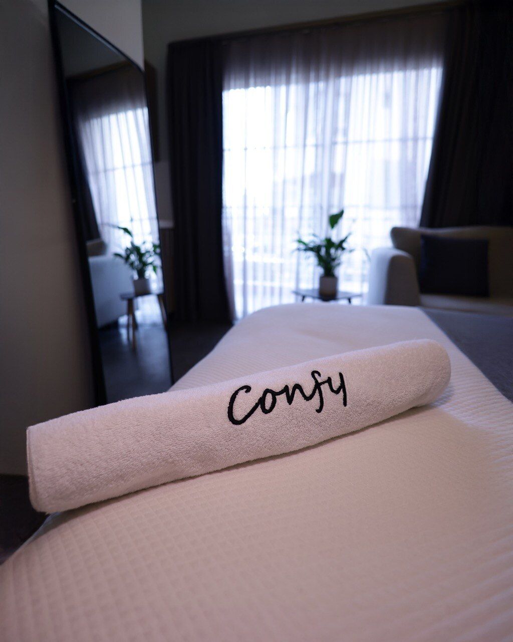 Una cama bien hecha con un almohadón que dice 'Confy' en una habitación de hotel.