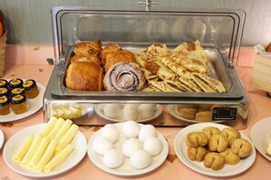 A buffet with various food items including pastries, flatbreads, and small round snacks. - COMFY APART HOTEL (Beirut)