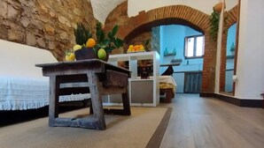 A rustic interior with a stone wall, a wooden table, and a kitchen area with a window. - Apartamento Turistico Arco Jerez Zafra (Zafra)