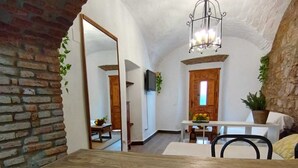 A rustic dining area with a wooden table and chairs, a hanging light fixture, and a brick wall. - Apartamento Turistico Arco Jerez Zafra (Zafra)