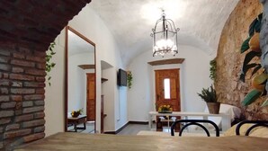 A rustic interior with exposed brick walls, a wooden table, and a hanging light fixture. - Apartamento Turistico Arco Jerez Zafra (Zafra)