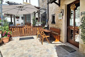 Eine Terrasse im Freien mit einem Holztisch und -stühlen, einem Holzzaun und Blumentöpfen.