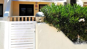 Un edificio blanco con balcón, una reja y una palmera.