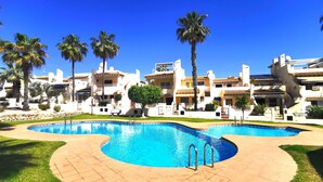 Un resort con una piscina grande, palmeras y edificios de estilo mediterráneo.