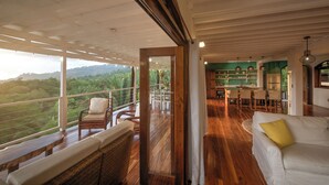 Une pièce spacieuse avec un plancher en bois, un canapé blanc et un coin repas avec des chaises.