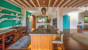 Une cuisine spacieuse avec des meubles en bois, un îlot central et un mur d’accent d’un vert vif.