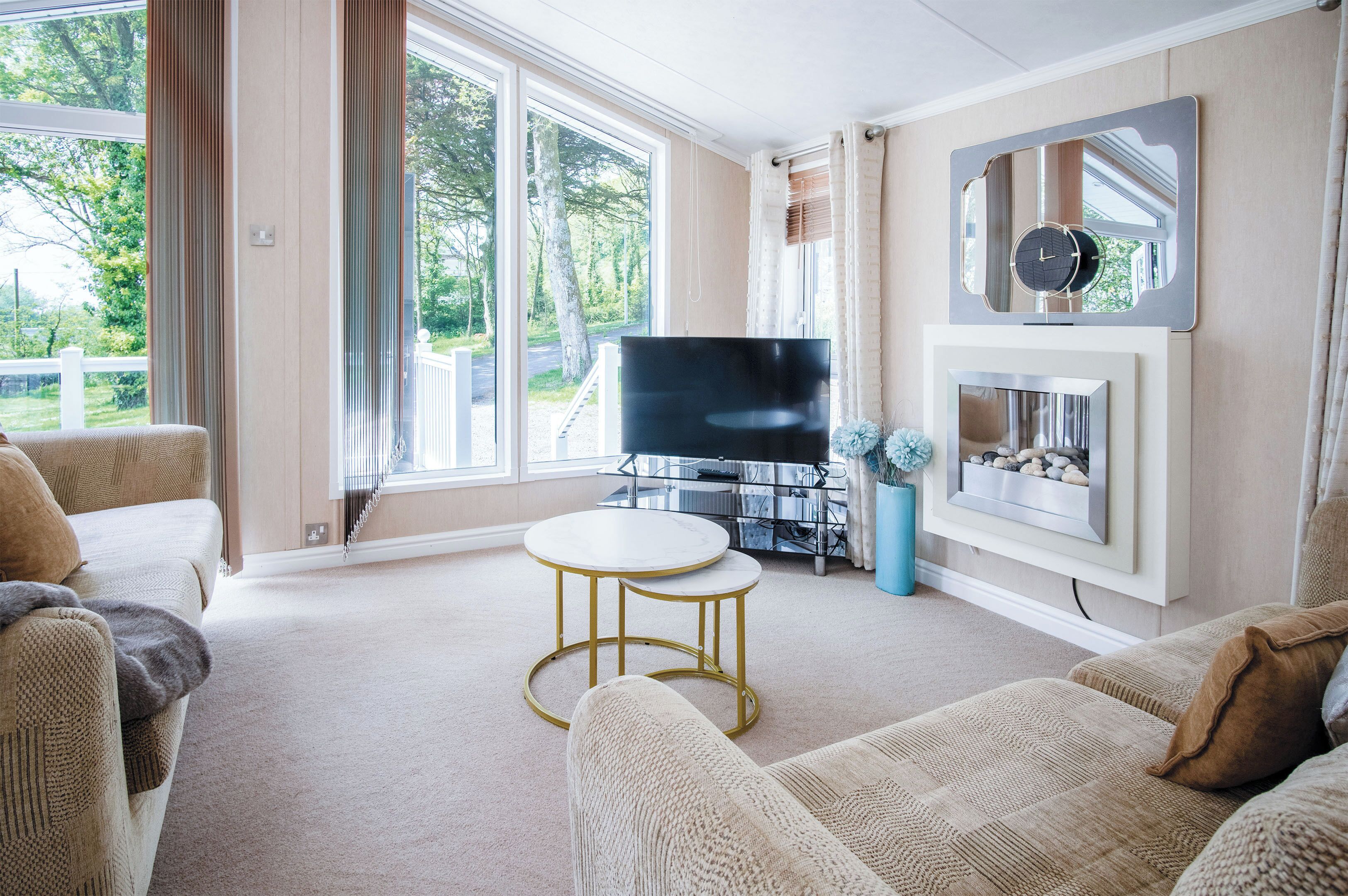 Ein Wohnzimmer mit Fernseher, Kamin und großem Fenster.