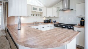 Une cuisine moderne dotée d’un îlot central, de meubles blancs et d’appareils électroménagers en acier inoxydable.