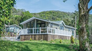 Une maison à deux étages dotée d’un porche couvert et d’une terrasse en bois.