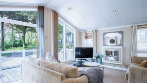 Un salon spacieux doté d’une grande fenêtre, d’un téléviseur à écran plat, d’une cheminée et d’un coin salon confortable.