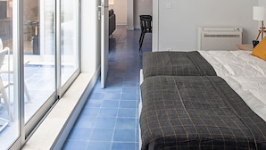 A hotel room with a bed, a chair, a table, and a sliding glass door leading to an outdoor area. - Piso Azul (Lisbon)