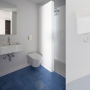 Un baño moderno con lavamanos, inodoro y ducha blancos.