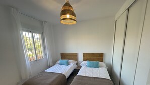 A room with two beds, a hanging light fixture, and a window with curtains. - Sunstay Relax 69 Rio Marina Nerja (Nerja)