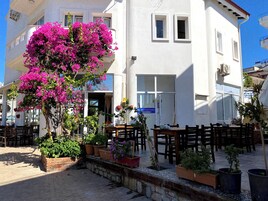 Un edificio blanco con balcón, plantas en macetas y mobiliario exterior.