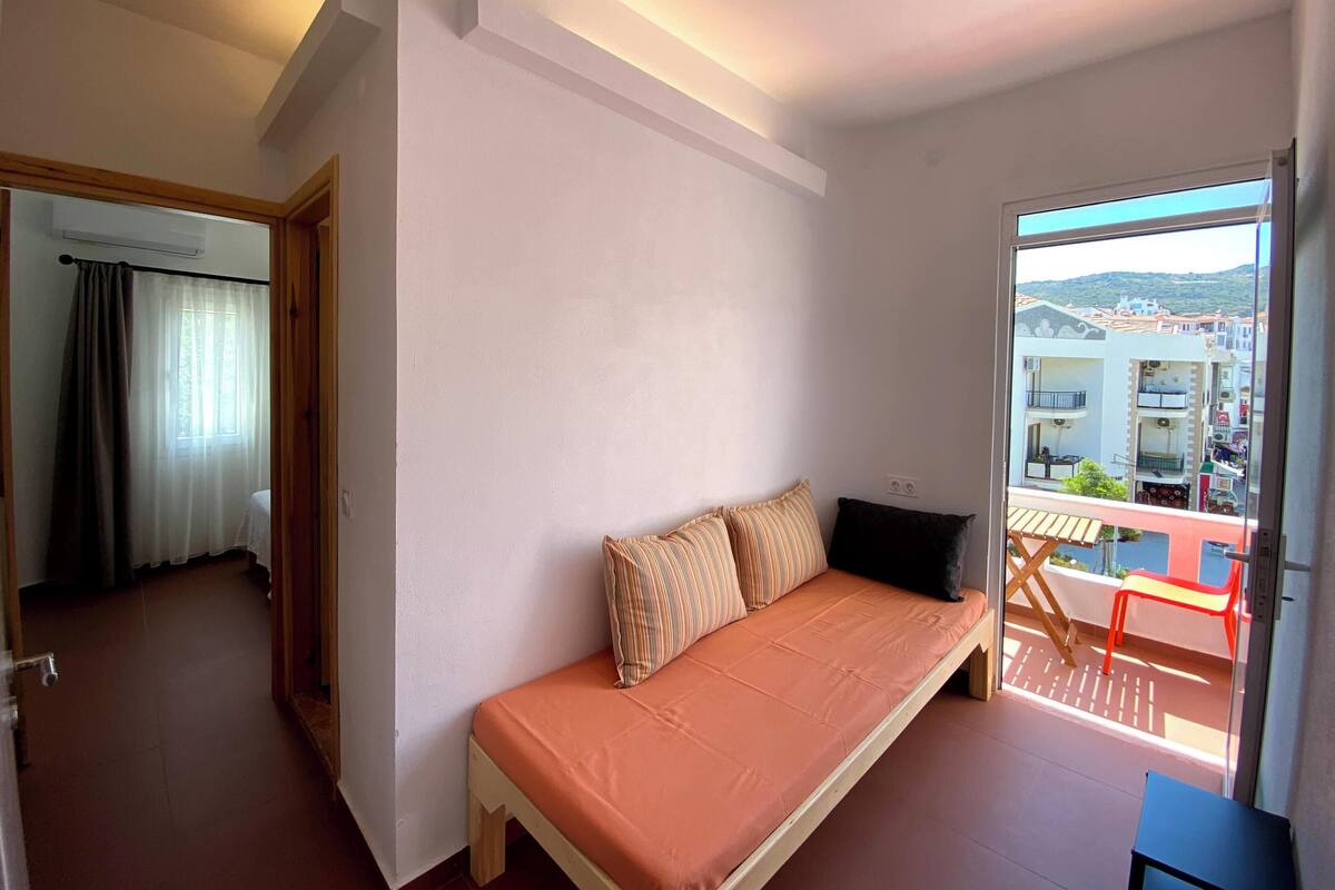 A bedroom with a bed, a window, and a view of buildings.
