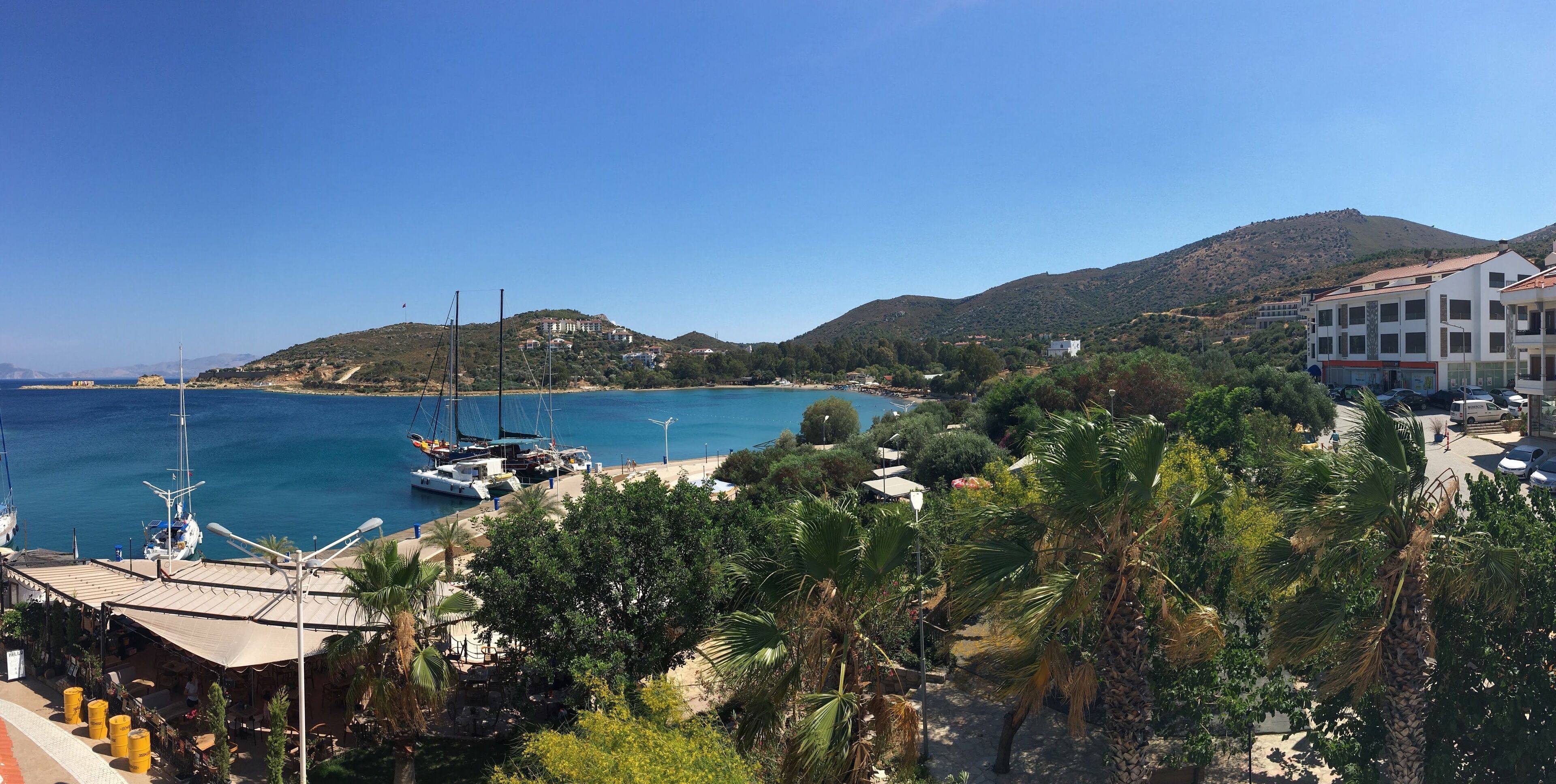 Una zona costera con un puerto deportivo, edificios y un paisaje montañoso.