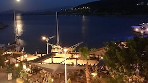 Un restaurant situé au bord de l’eau, avec une terrasse, une vue sur la mer et un bateau amarré à proximité.