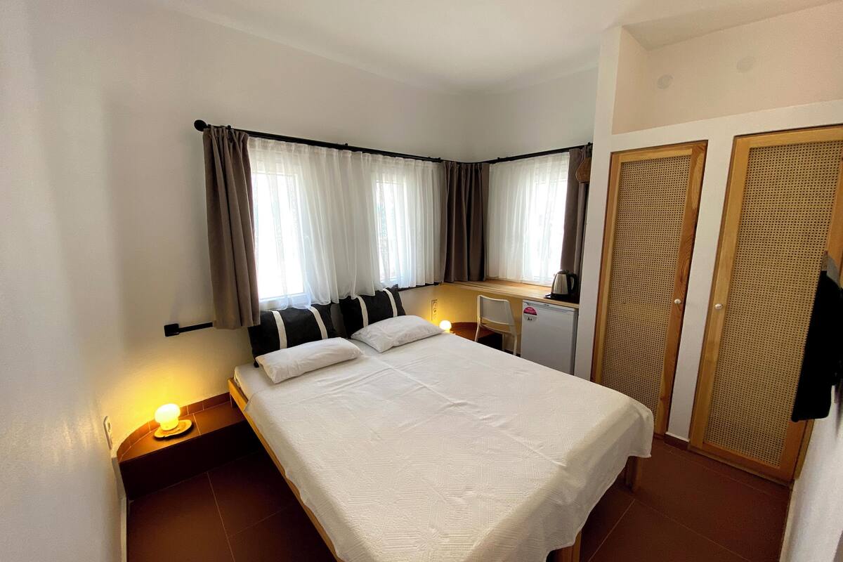 A hotel room with a single bed, a desk with a kettle, and a wardrobe.