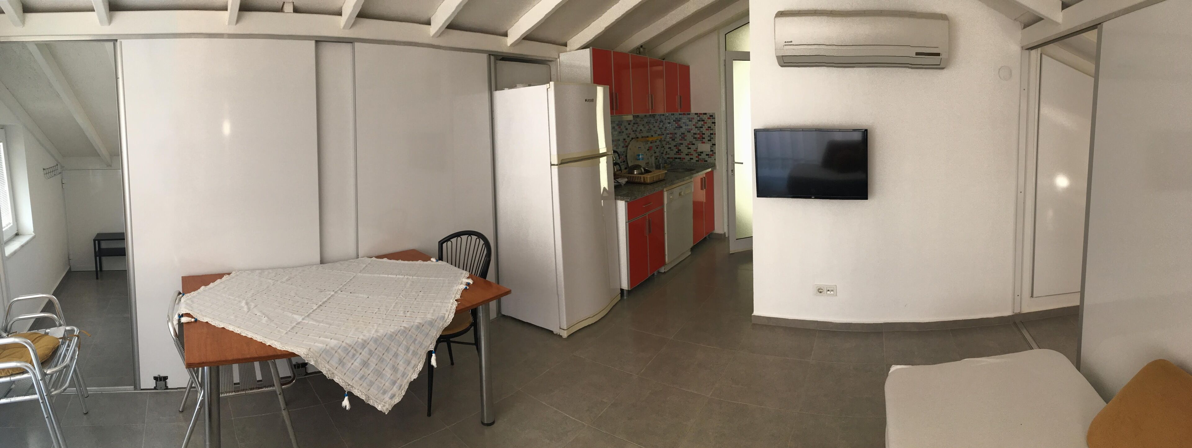 A compact kitchen with a refrigerator, a microwave, and a tiled backsplash.