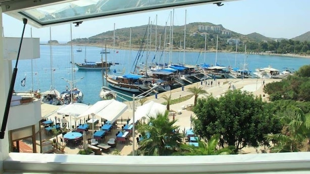 Un port de plaisance avec des bateaux amarrés, une plage avec des parasols et un bâtiment en arrière-plan.