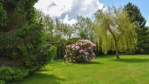 A garden with a swing set, a large bush of pink flowers, and a variety of trees. - House Jaulice - 8 min Pont l'Evêque - 10 people (Le Torquesne)