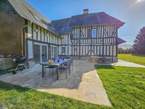 A two-story Tudor-style house with a patio area featuring a table set for dining, outdoor seating, and a grill. - House Jaulice - 8 min Pont l'Evêque - 10 people (Le Torquesne)
