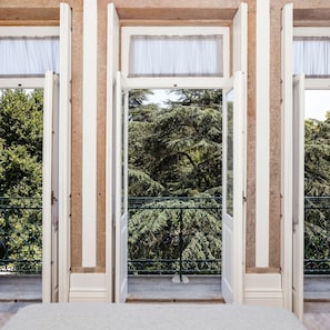 Une vue à travers une fenêtre donnant sur des arbres et une rambarde métallique verte.