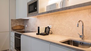 A modern kitchen with a built-in microwave, a coffee machine, and a stainless steel sink. - Ando Living - São Nicolau Townhouse (Lisbon)
