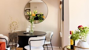 A dining area with a round table, two chairs, a vase with flowers, and a mirror on the wall. - The Waterlow Park Wonder - Trendy 2bdr With Study Room and Patio (London)