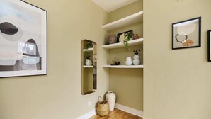 A hallway with a mirror, shelves with decorative items, and a framed picture on the wall. - The Waterlow Park Wonder - Trendy 2bdr With Study Room and Patio (London)