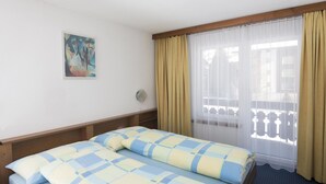 Une chambre d’hôtel avec deux lits, un tableau au mur, une fenêtre avec des rideaux et une vue sur l’extérieur.