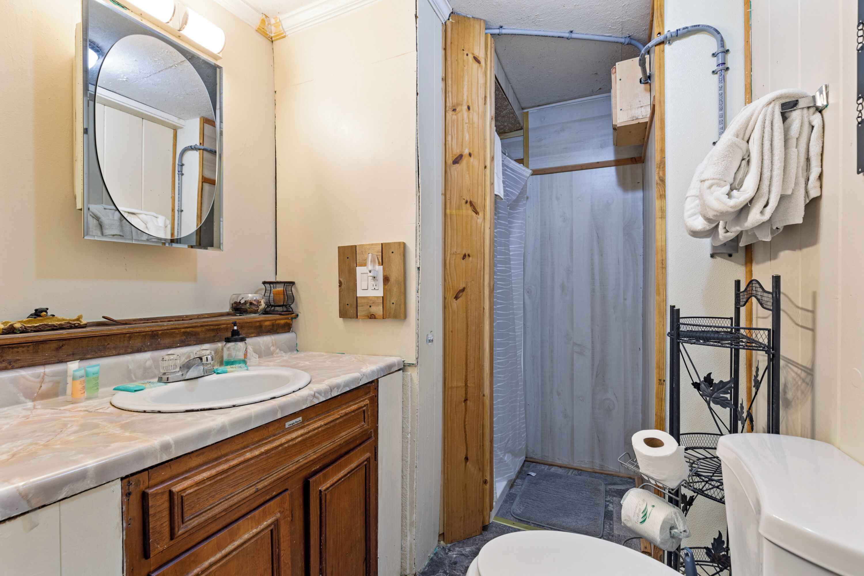 A bathroom with a wooden vanity, a sink, a mirror, and a shower enclosure.