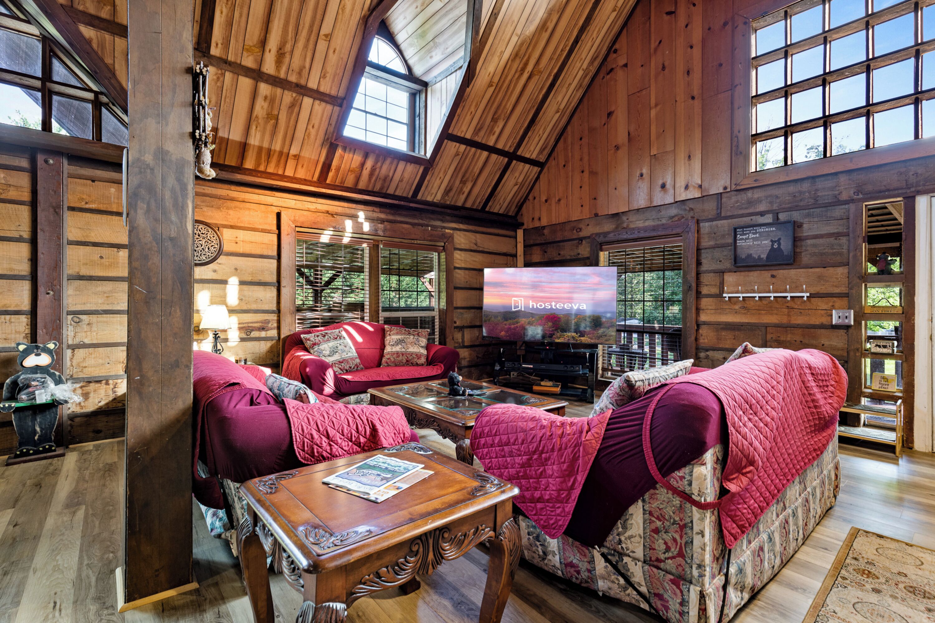 A log cabin interior with a cozy living area featuring a sofa, armchairs, and a television.