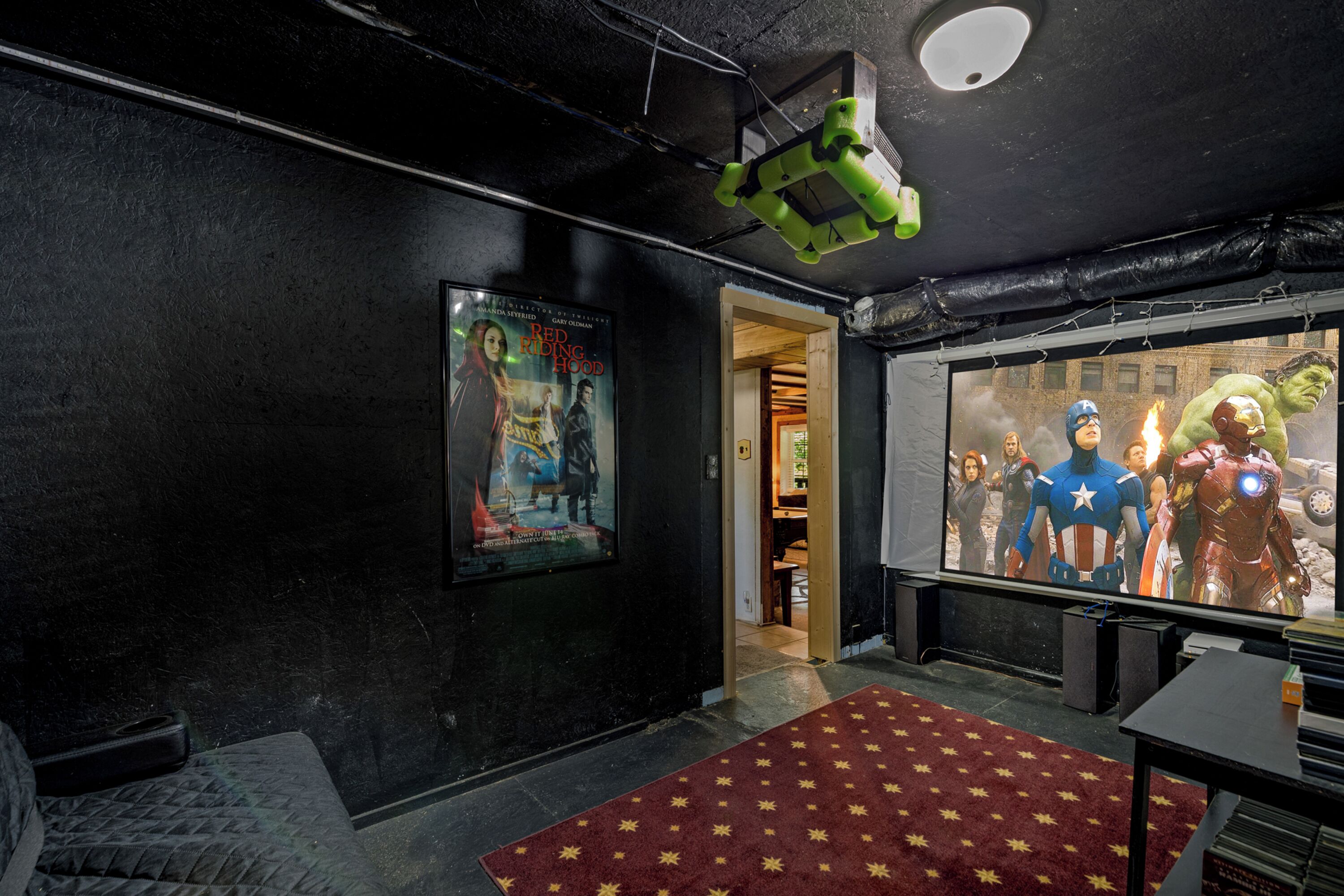 A movie theater with a large screen, posters on the wall, and a red carpet.