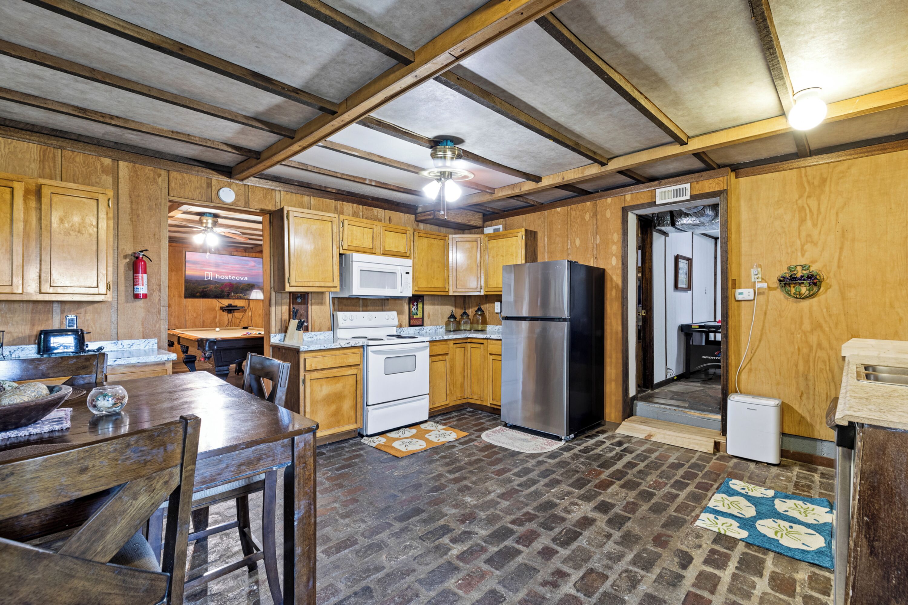 A kitchen with wooden cabinets, a microwave, a refrigerator, and a dining table with chairs.