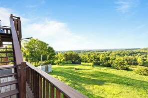 A wooden deck with a view of a lush green landscape and distant hills. - Hillbilly Highrise (Sevierville)