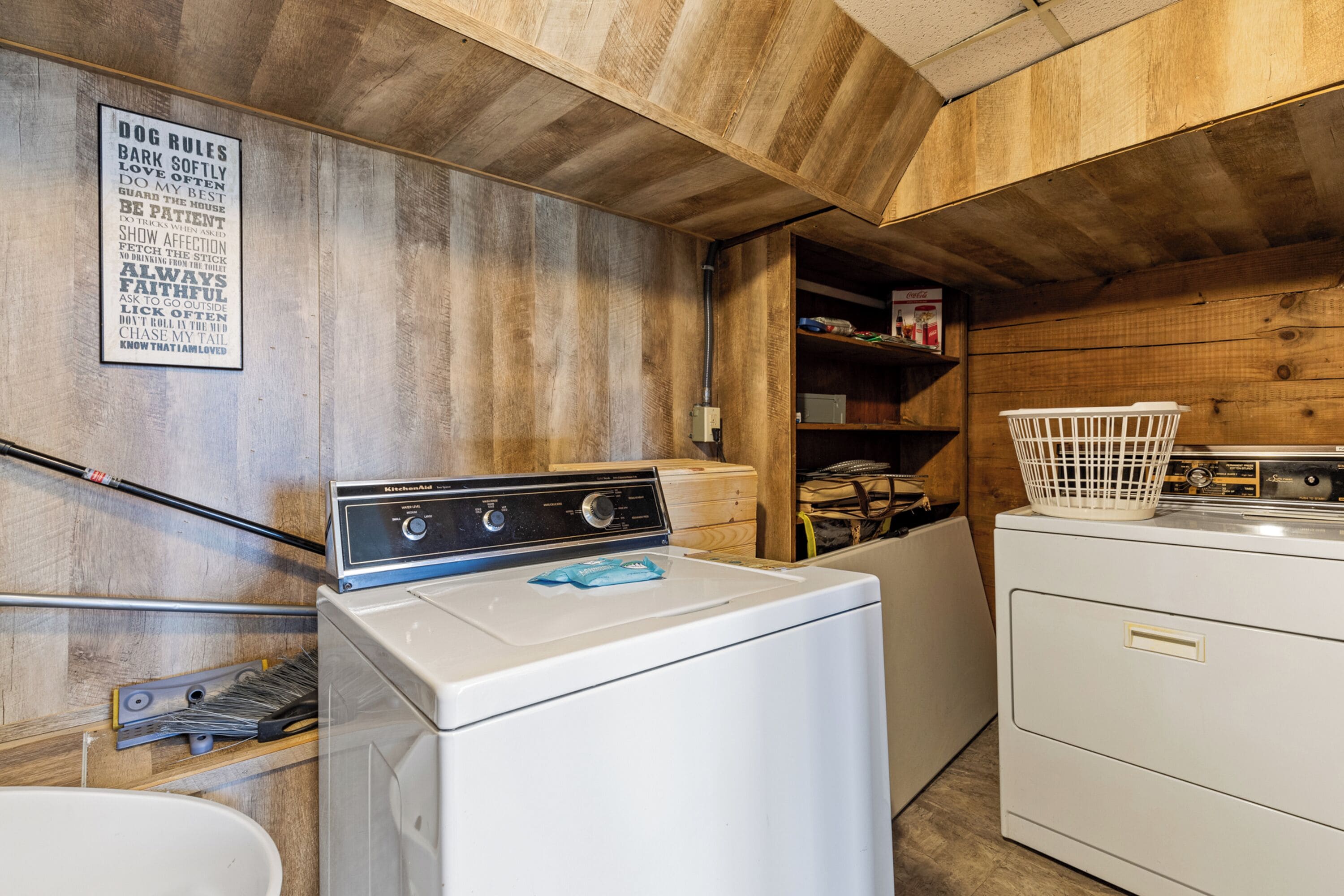 A laundry area with a washing machine, dryer, and a sign listing dog rules.