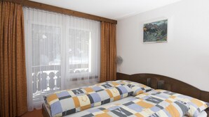 Una habitación de hotel con cama, cortinas, un cuadro en la pared y una ventana con persianas.