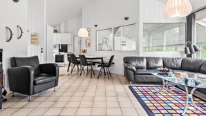 Una sala de estar moderna con chimenea, sofás de cuero, un comedor y ventanas grandes.