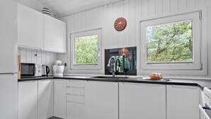 Una cocina moderna con armarios blancos, un microondas, una cafetera y una barra de pan sobre la encimera.
