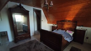 Ein Schlafzimmer mit einem hölzernen Bett, einem Schminktisch, einem Spiegel und einem Nachttisch.
