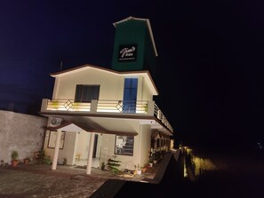 Un edificio de dos pisos con un balcón, un letrero que dice "Jim's Inn" y una escalera que lleva a la entrada.