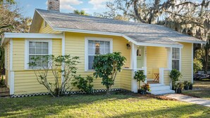 A yellow house with a gabled roof, white trim, and a small porch with steps.