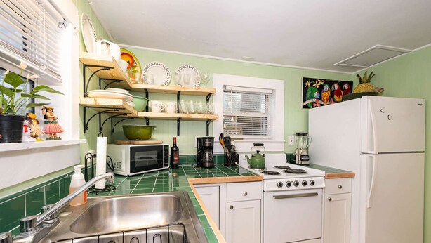 A compact kitchen with a sink, microwave, stove, and white refrigerator. - Lookout · Relaxing 2/1 Oasis near River · 9 min to Beach (Melbourne)