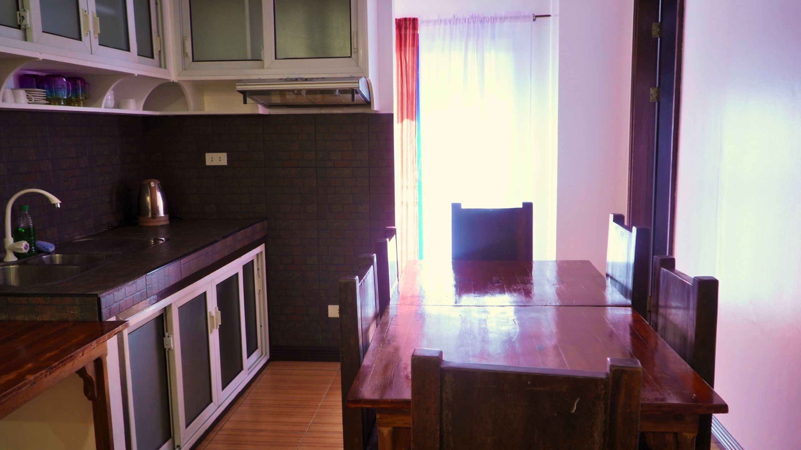 A kitchen with a wooden table and chairs, a sink, and cabinets.